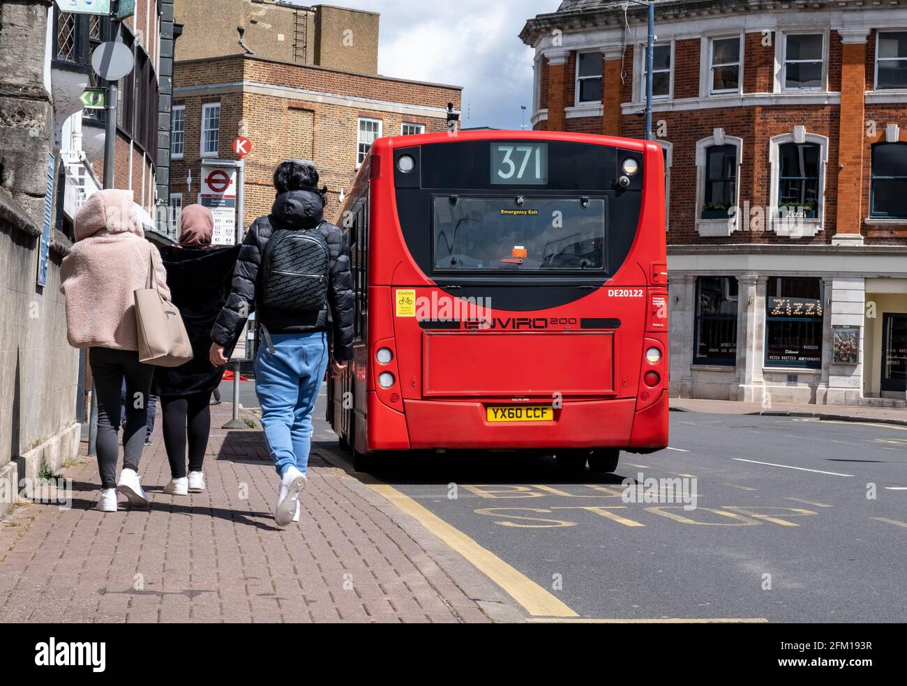 Kingston Upon Thames London UK, May 04 2021, Three Anonymous Woman Walking Along Pavementment Next To A Red Single Decker Bus On A Town Centre High St Stock Photo
