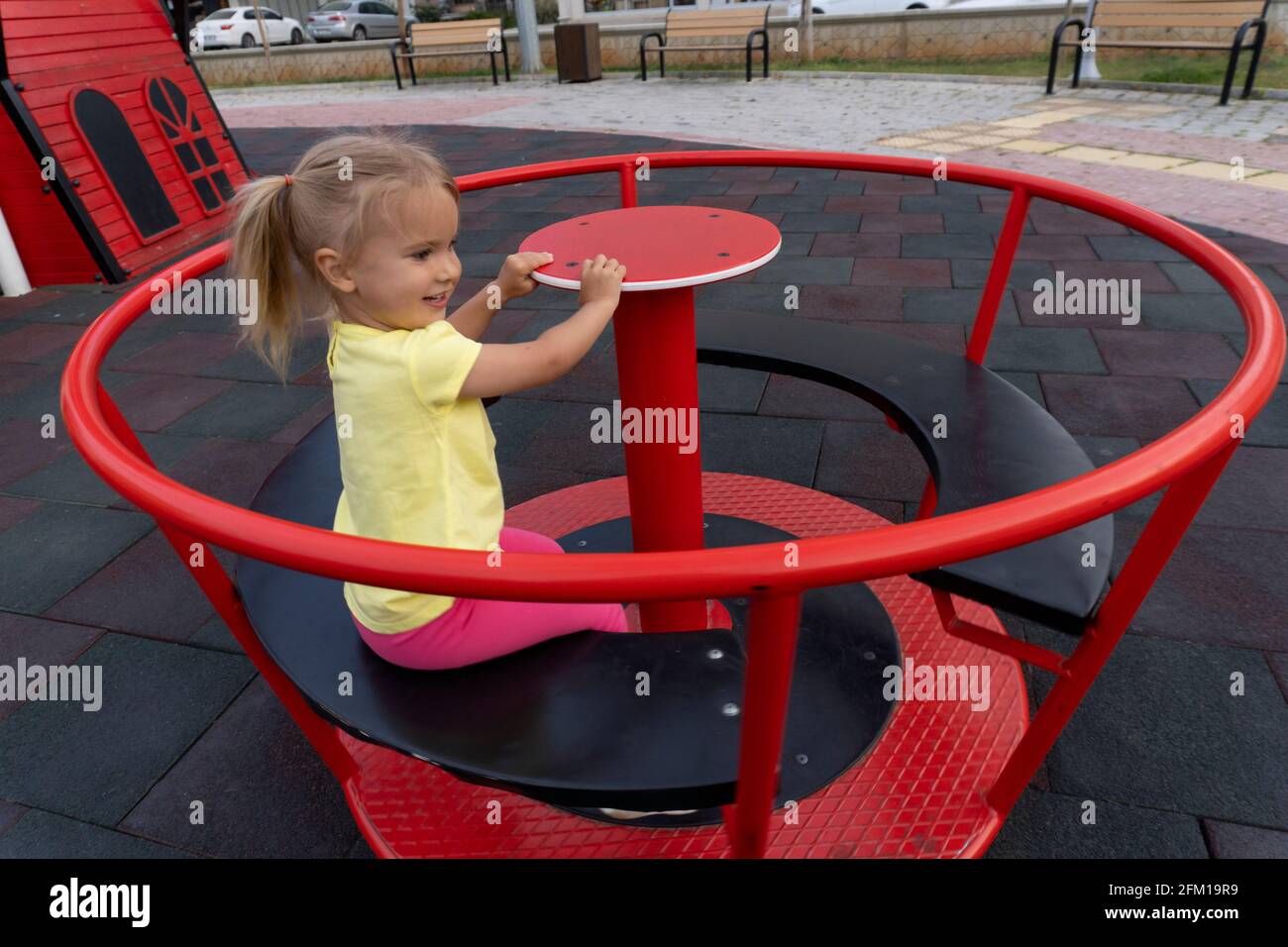 Cute little caucasian child riding on spining swing at playground Stock Photo