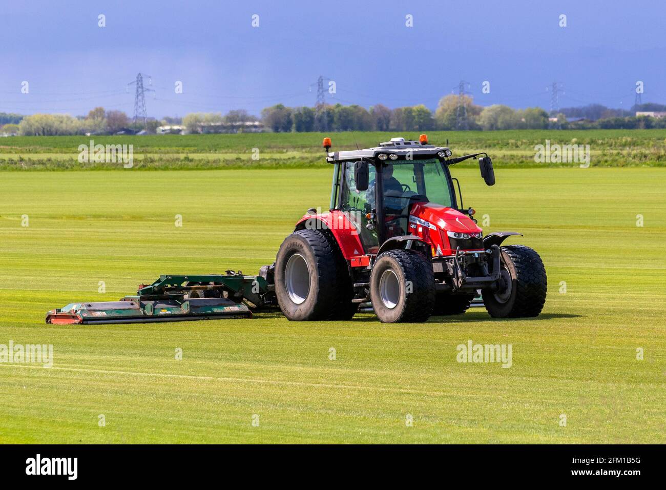 Tarleton UK Weather 5th May 2021; Bright sunny start to the day for commerical turf growers in Lancashire mowing grassland with the award winning Massey Ferguson farm tractor 5713;   Sod is typically used for lawns, golf courses, and new housing around the world. In residential construction, it is sold to landscapers, home builders or home owners who use it to establish a lawn quickly and avoid soil erosion. Credit MediaWorldImages/AlamyLiveNews Stock Photo
