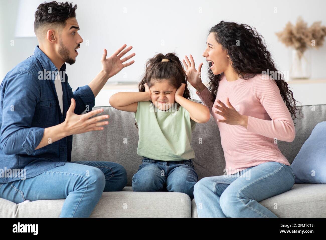 Parental Quarrels. Arab Man And Woman Arguing In Front Of Their Chils Stock Photo