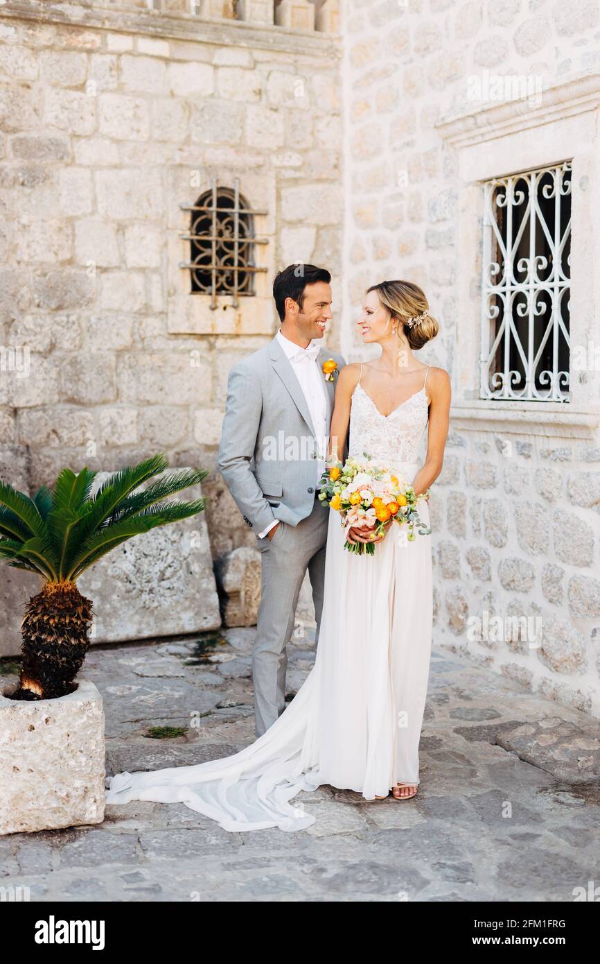The bride and groom stand in front of a beautiful old house with forged ...