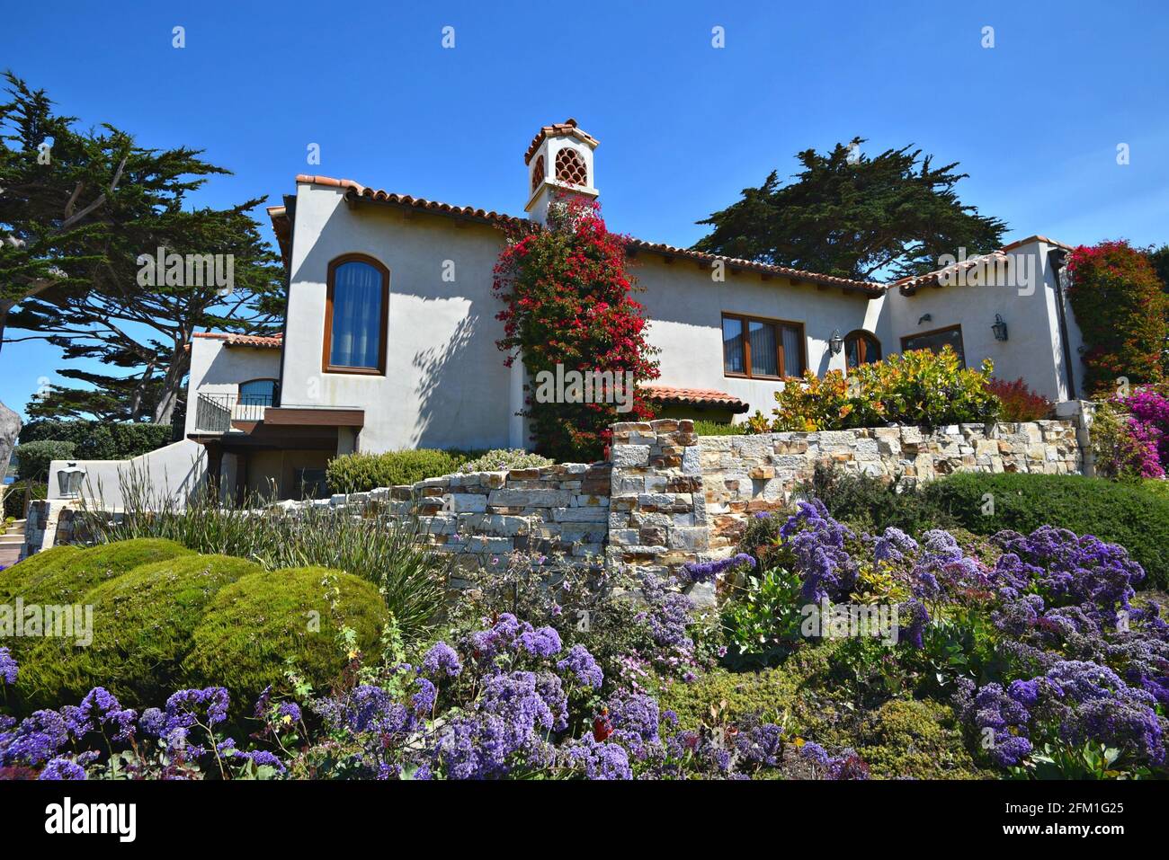 Exterior view of a luxury Spanish style hacienda with a colorful garden