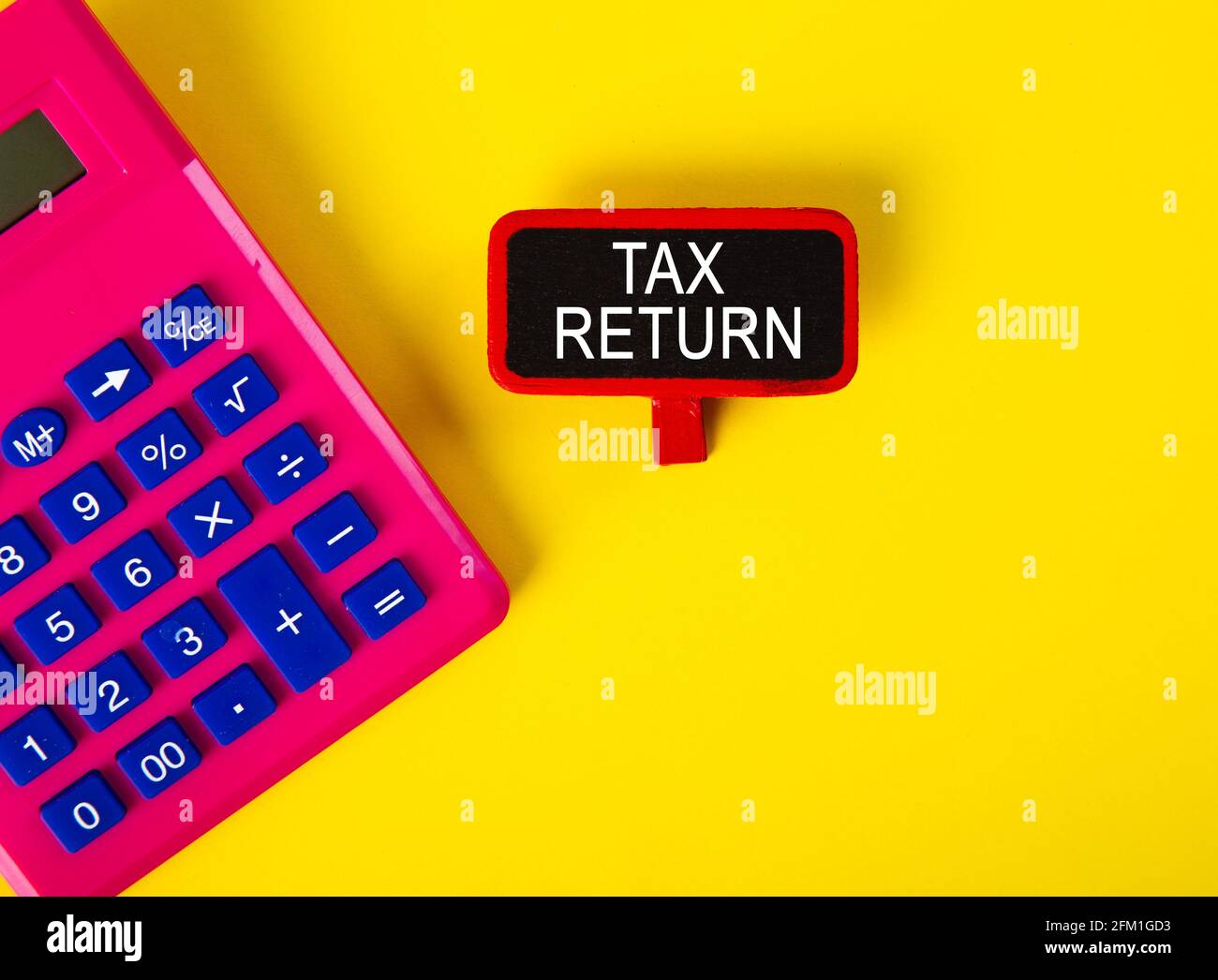 Top view of calculator and a tag with TAX RETURN word on yellow