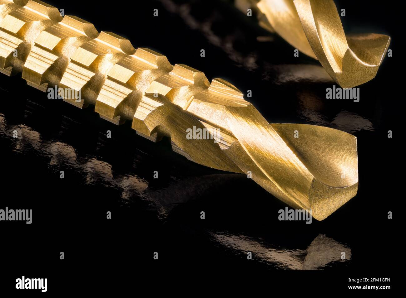 CLose-up of sharp titanium coated drill bits tips in artistic still life. Gold steel tools with serrations for horizontally drilling after making hole. Stock Photo