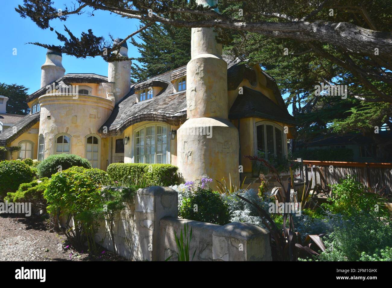 Exterior view of a fairy tale cottage surrounded by cypress trees in