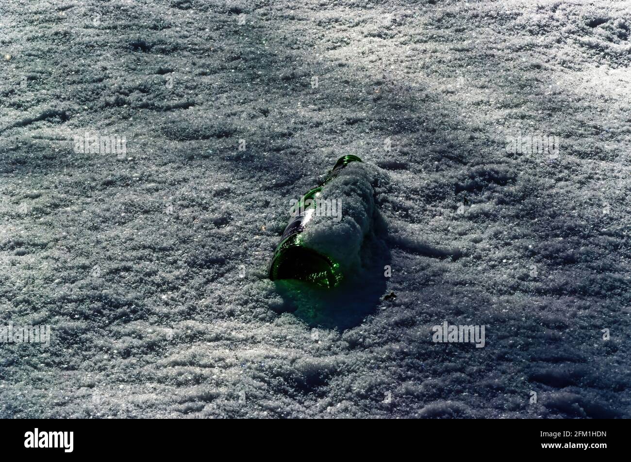 glass bottle lying in the snow, garbage Stock Photo