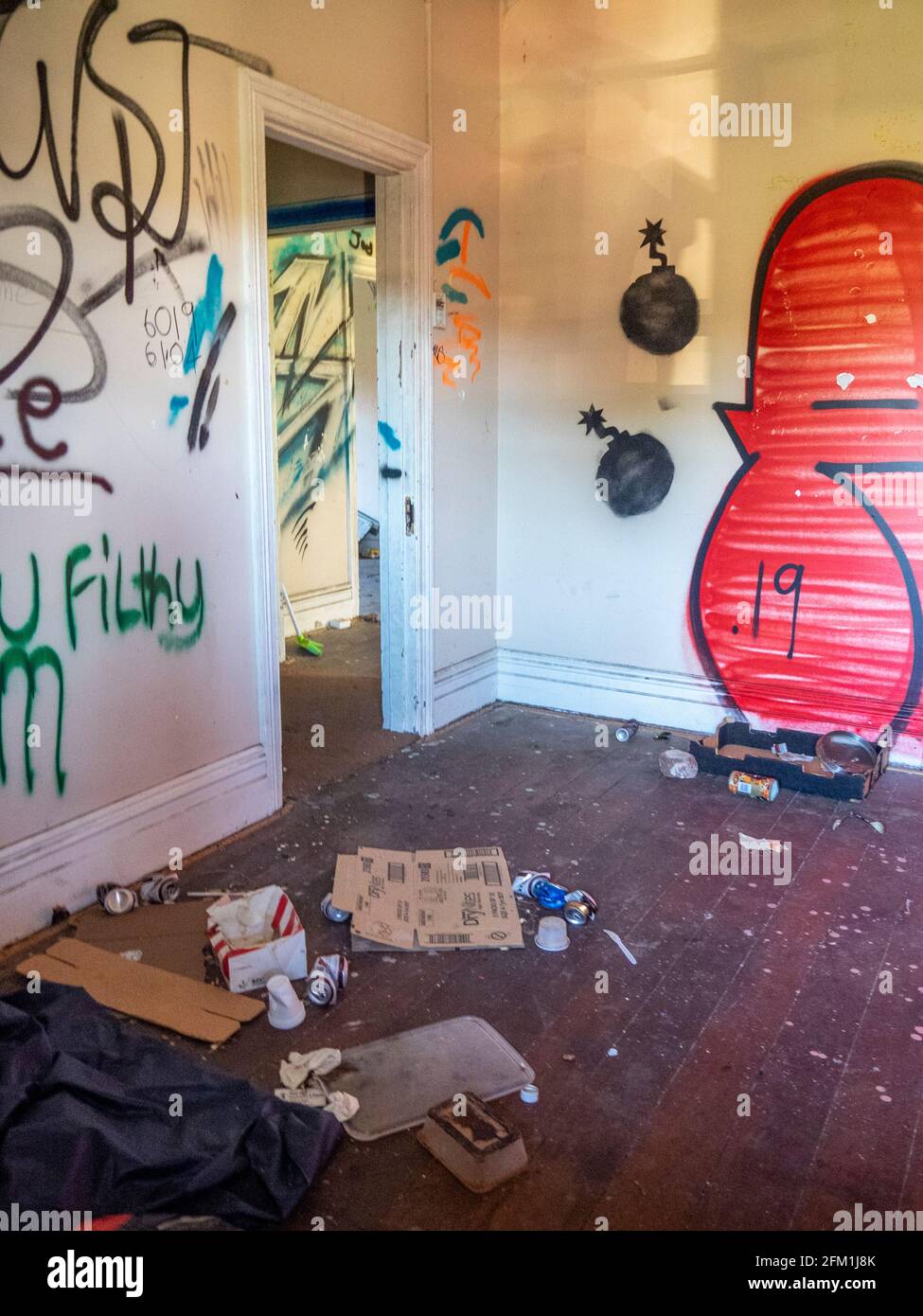 Litter on floor and graffiti and tags on wall in an abandoned house. Stock Photo