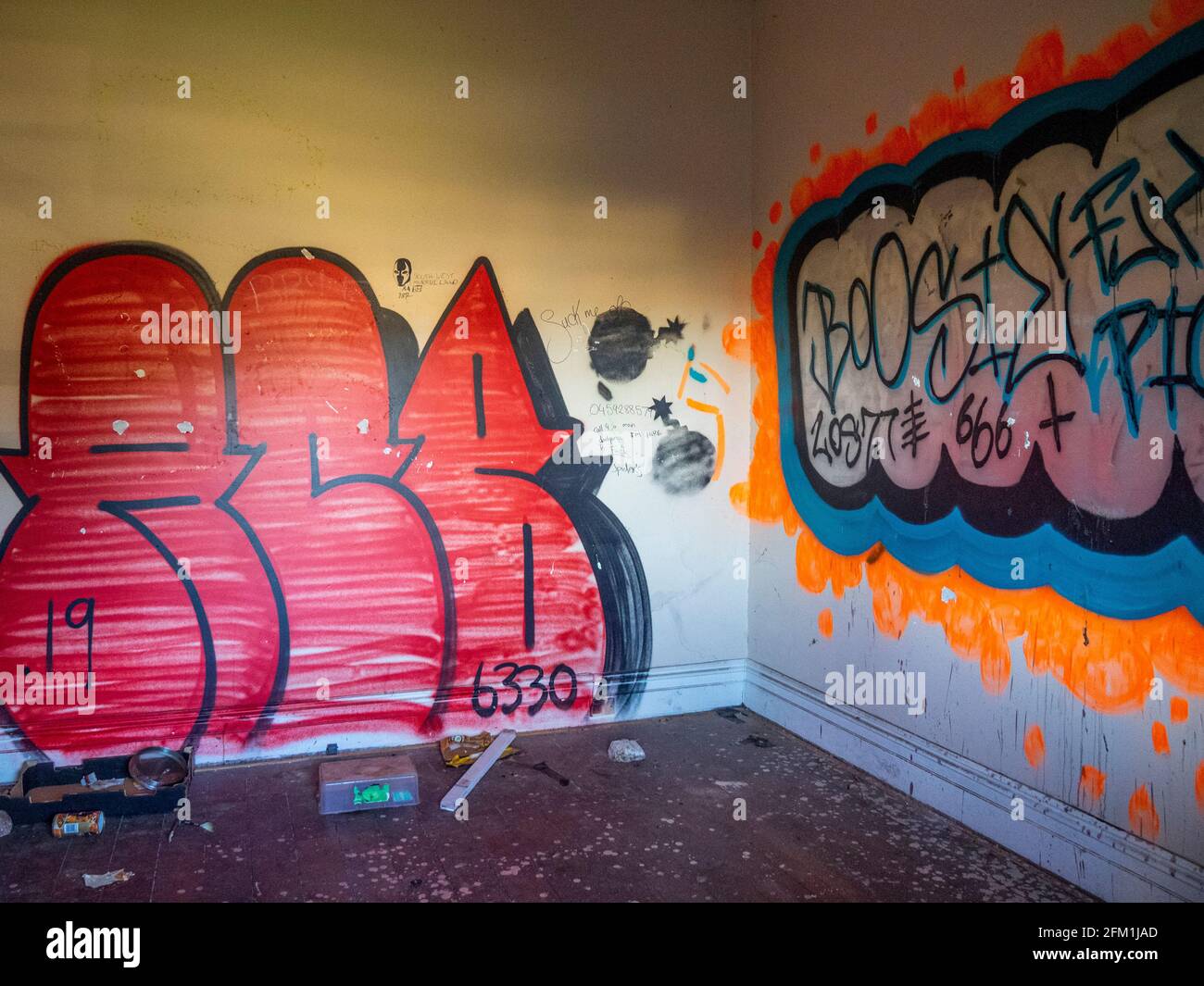Litter on floor and graffiti and tags on wall in an abandoned house. Stock Photo