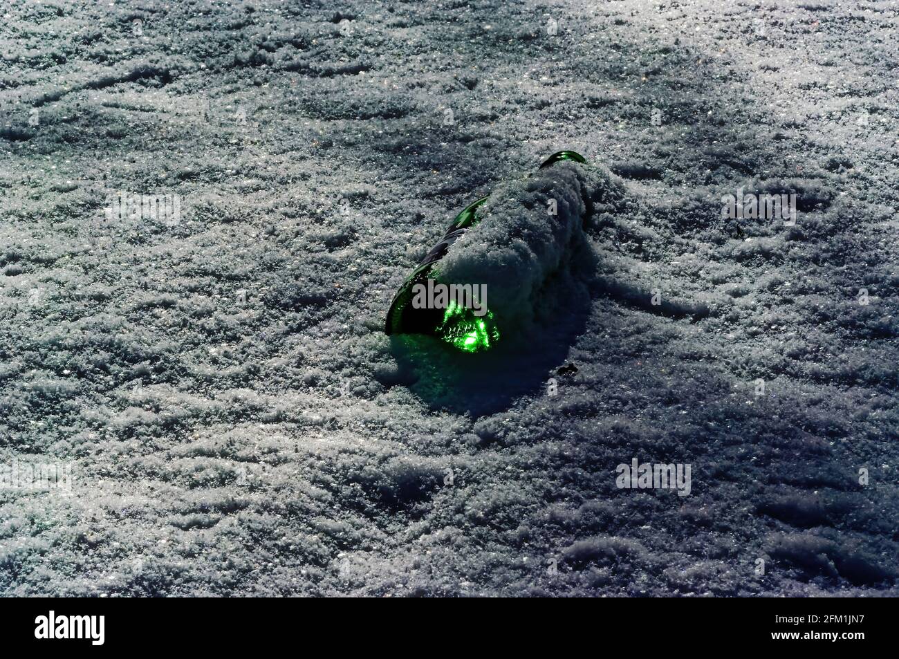 glass bottle lying in the snow, garbage Stock Photo