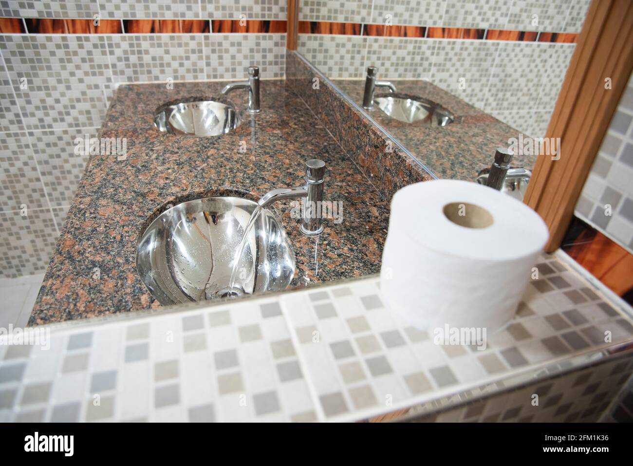 Modern prívate school bathroom, with new tiles, sink, toilette paper. Stock Photo