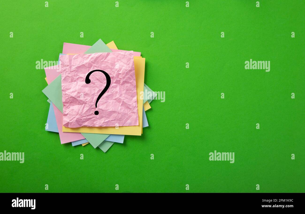 Question mark drawn on notepad. Over green background with copy space. Stock Photo