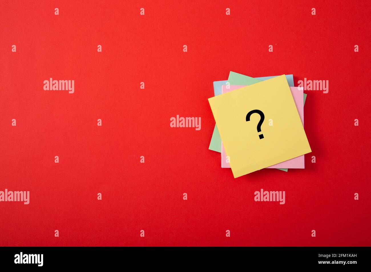 Question mark drawn on notepad. Over red background with copy space. Stock Photo