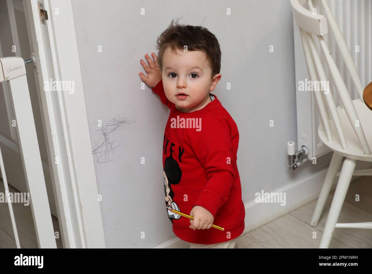 A young boy pictured drawing on the walls with a pencil in West Sussex, UK. Stock Photo