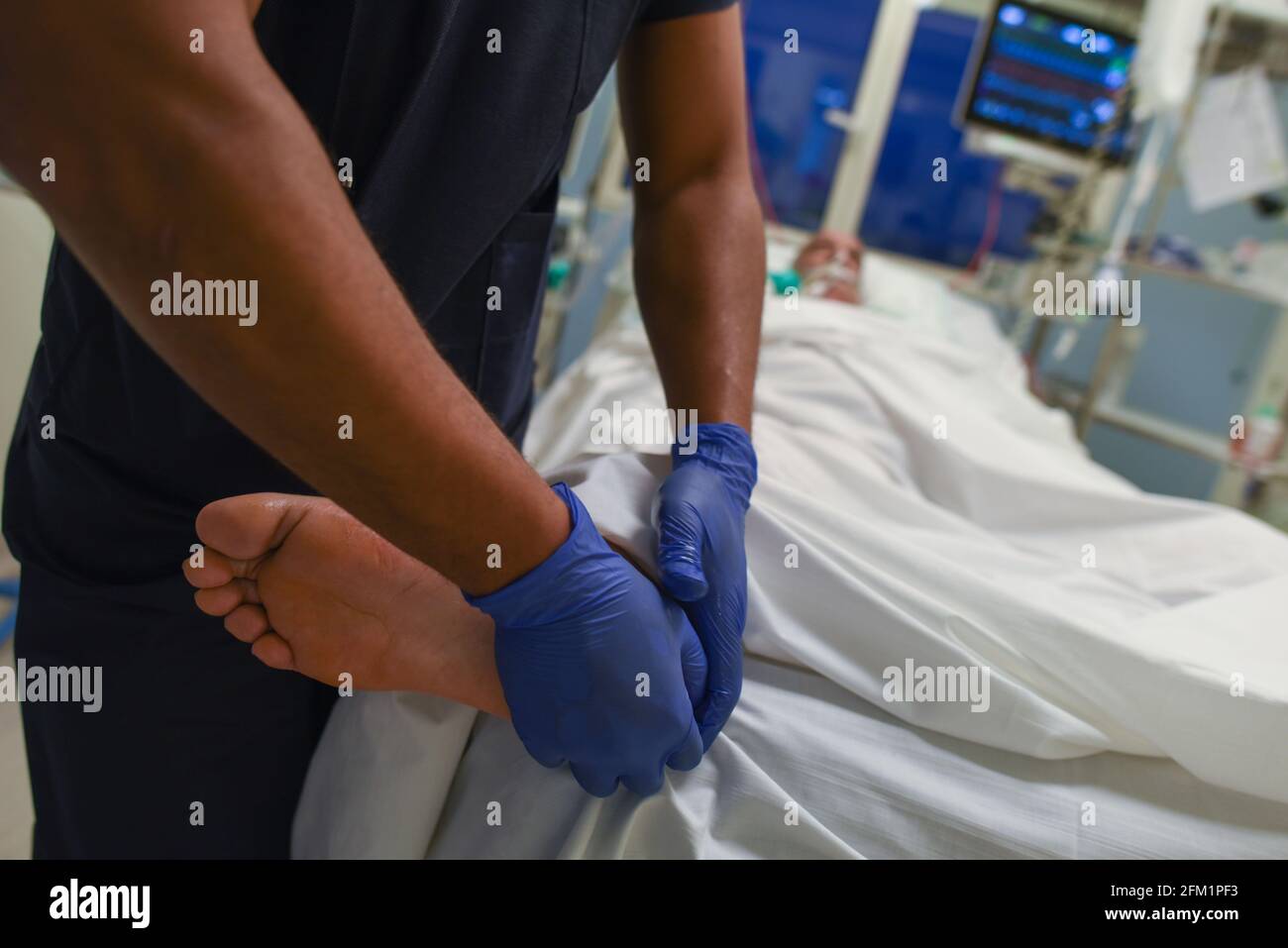 *** STRICTLY NO SALES TO FRENCH MEDIA OR PUBLISHERS - RIGHTS RESERVED ***November 19, 2020 - Stains, France: Healthcare workers do a massage on the feet of an intubated patient seriously sick with Covid-19 in the intensive care unit at the Clinique de l'Estree, during the second wave of the coronavirus pandemy. This massage aims to prevent bedsores. Staff said experience of the first wave of Covid allowed them to better treat patients. Stock Photo