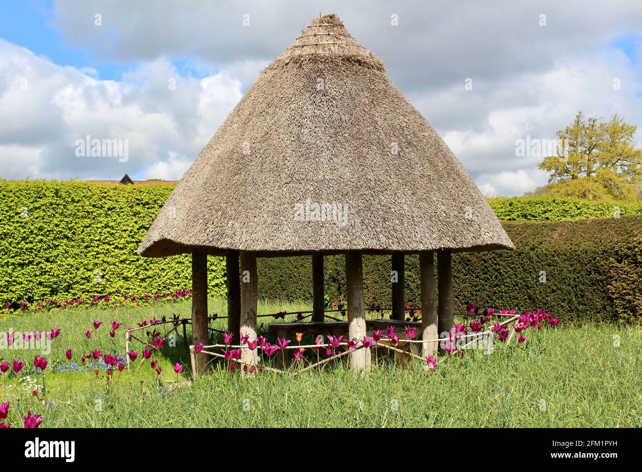 Arundel Castle Tulip Festival - 2021 - Rustic thatched summerhouse in a meadow backed by hedging. Stock Photo