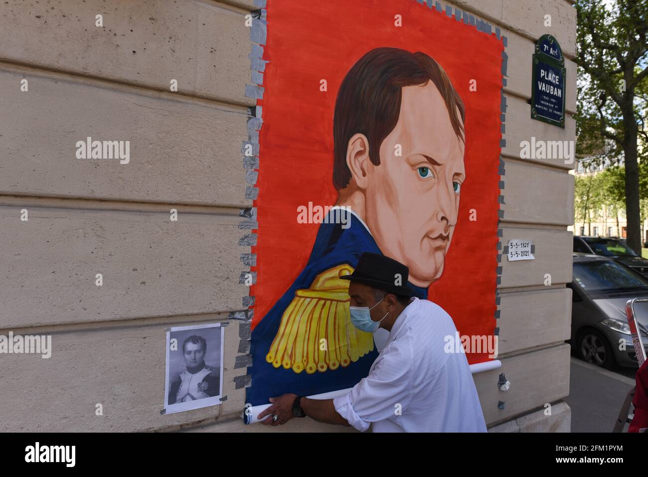 *** STRICTLY NO SALES TO FRENCH MEDIA OR PUBLISHERS - RIGHTS RESERVED ***May 05, 2021 - Paris, France: An artist unrolls a painting depicting French emperor Napoleon Bonaparte in front of the Invalides church, where the emperor's tomb is located, to mark the bicentenary of his death. Stock Photo