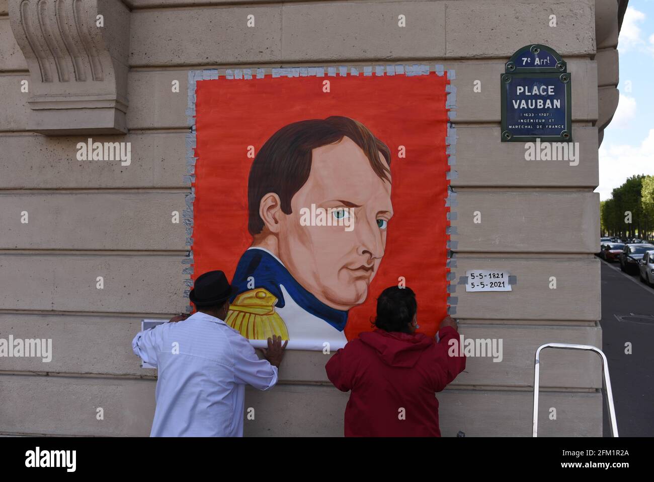 *** STRICTLY NO SALES TO FRENCH MEDIA OR PUBLISHERS - RIGHTS RESERVED ***May 05, 2021 - Paris, France: An artist unrolls a painting depicting French emperor Napoleon Bonaparte in front of the Invalides church, where the emperor's tomb is located, to mark the bicentenary of his death. Stock Photo