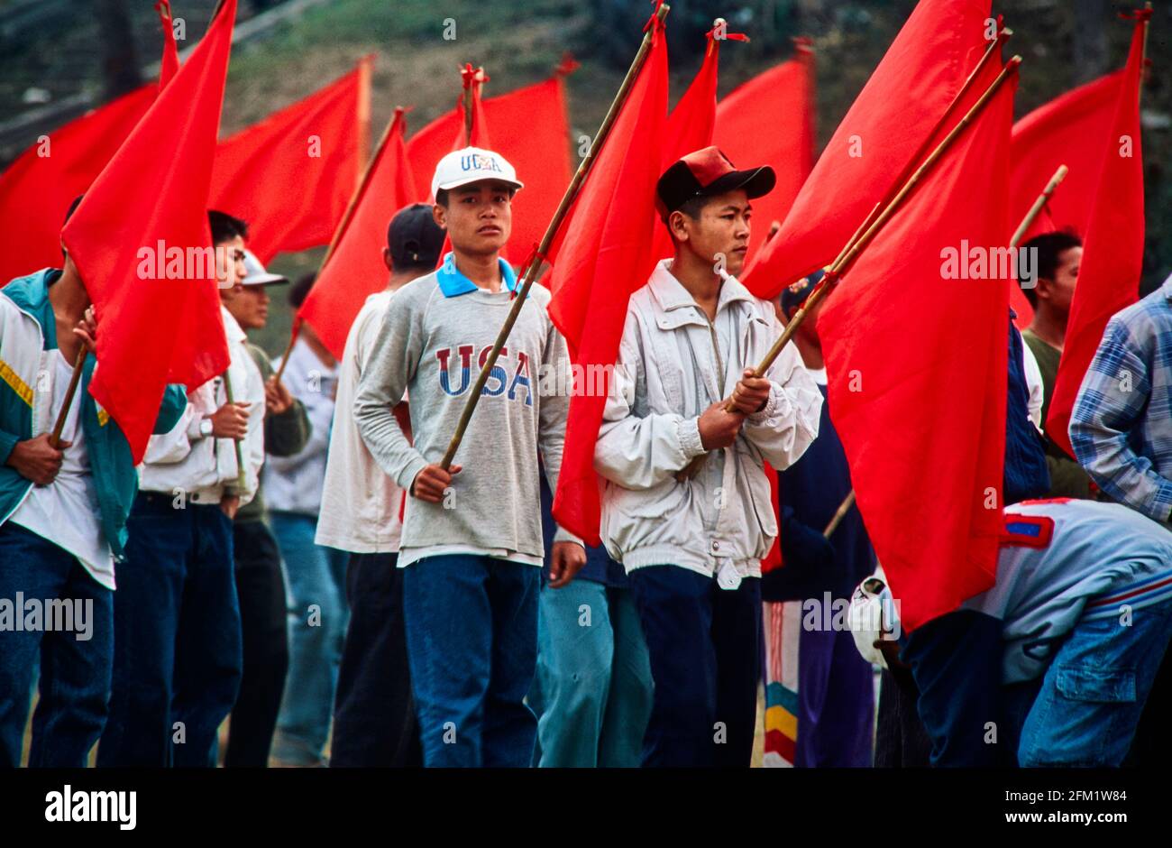 Students in Luang Prabang rehearse for a flag parade. Although the red, socialist flag is in hand, the capitalist USA is in mind. 12/1996 - Christoph Stock Photo