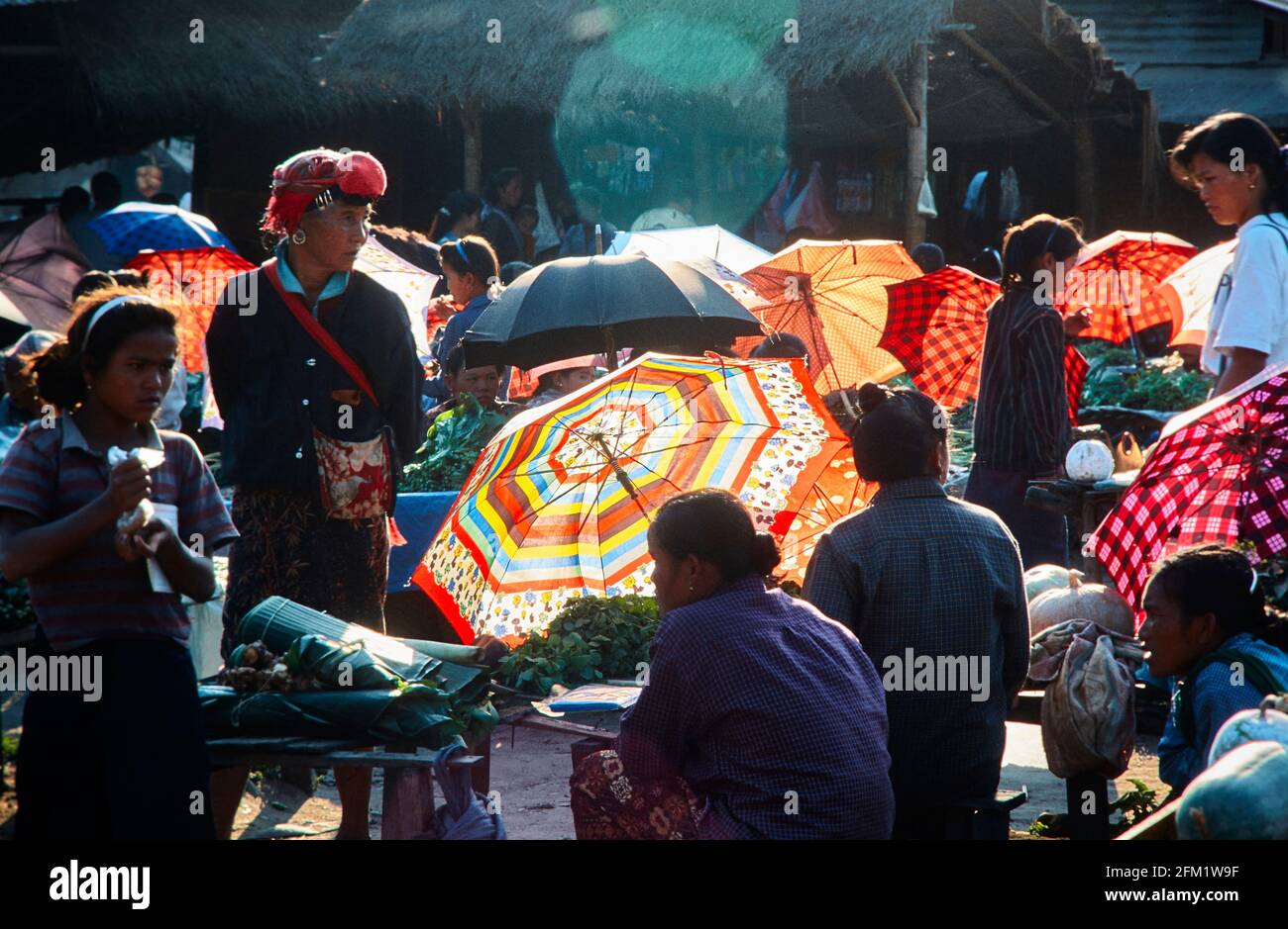Market day in Luang Namtha. Well shielded, the women sell vegetables and herbs. Under the protective umbrellas in quieter corners of the market, opium Stock Photo
