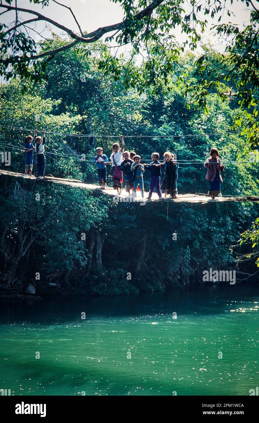 Courageous children on a swaying suspension bridge over a river in