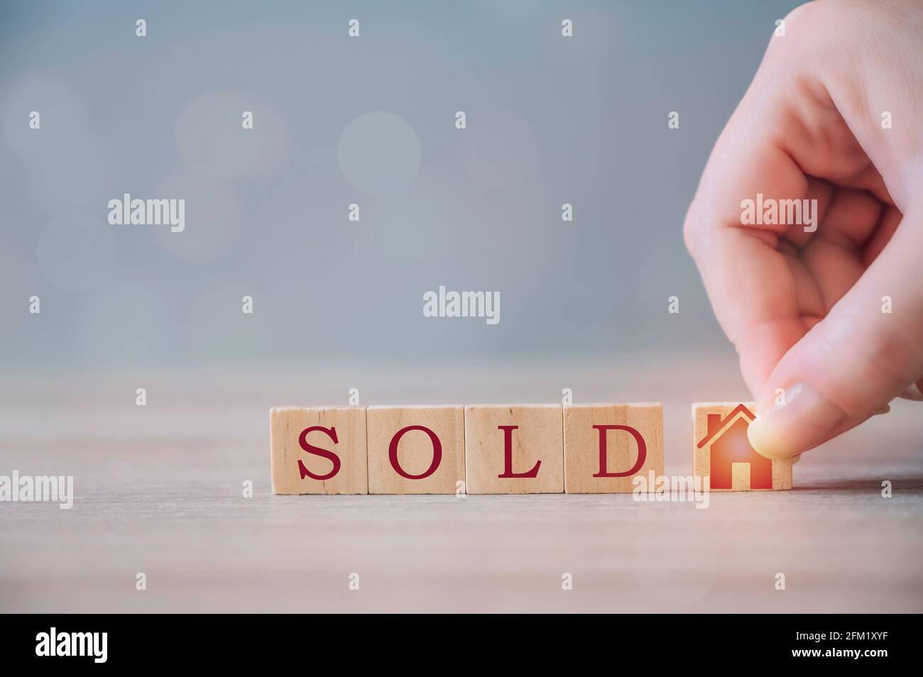 Hand puts a cube with a picture of the house to the word SOLD. Concept of selling a house, apartment, real estate. Property trade. Stock Photo