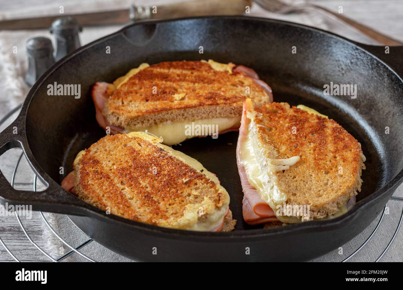 Rustic ham and cheese sandwich fried with sourdough bread in a cast iron pan Stock Photo