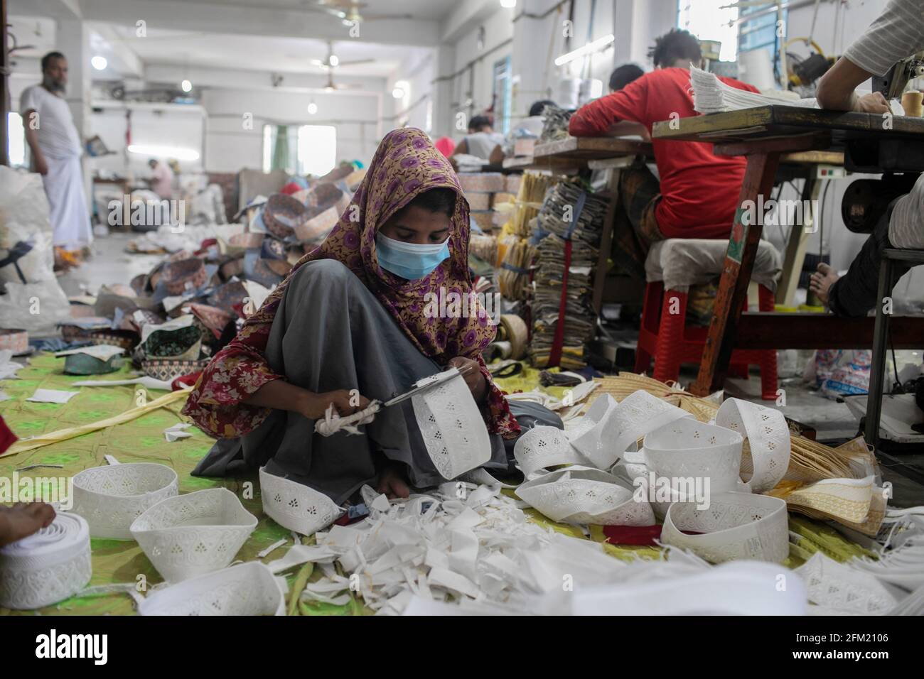 A worker wearing a face mask is seen making an Islamic Tupi (cap) at a