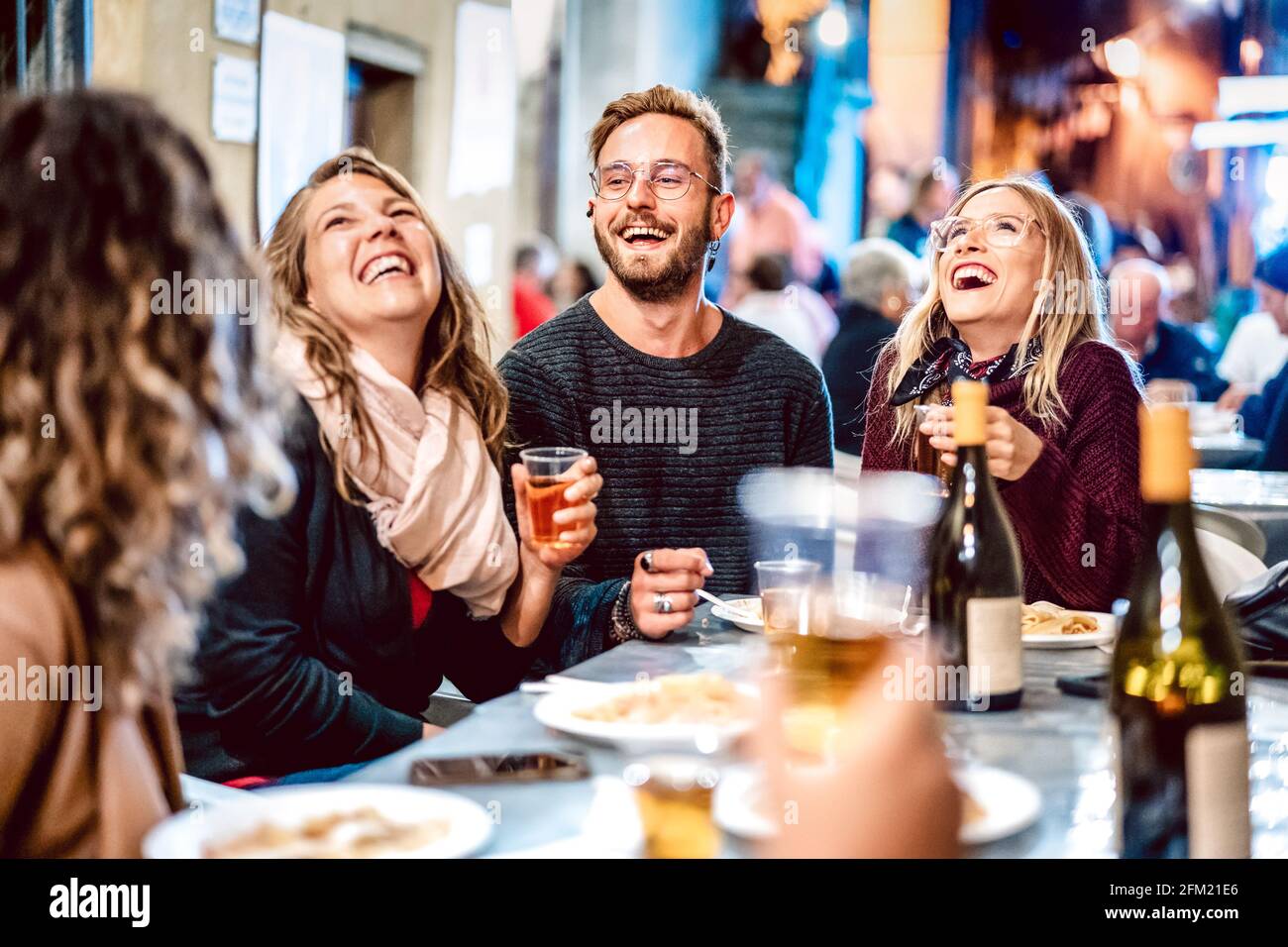 Happy friends having fun drinking white wine at street food festival - Young people eating local plate at restaurant reopening together Stock Photo