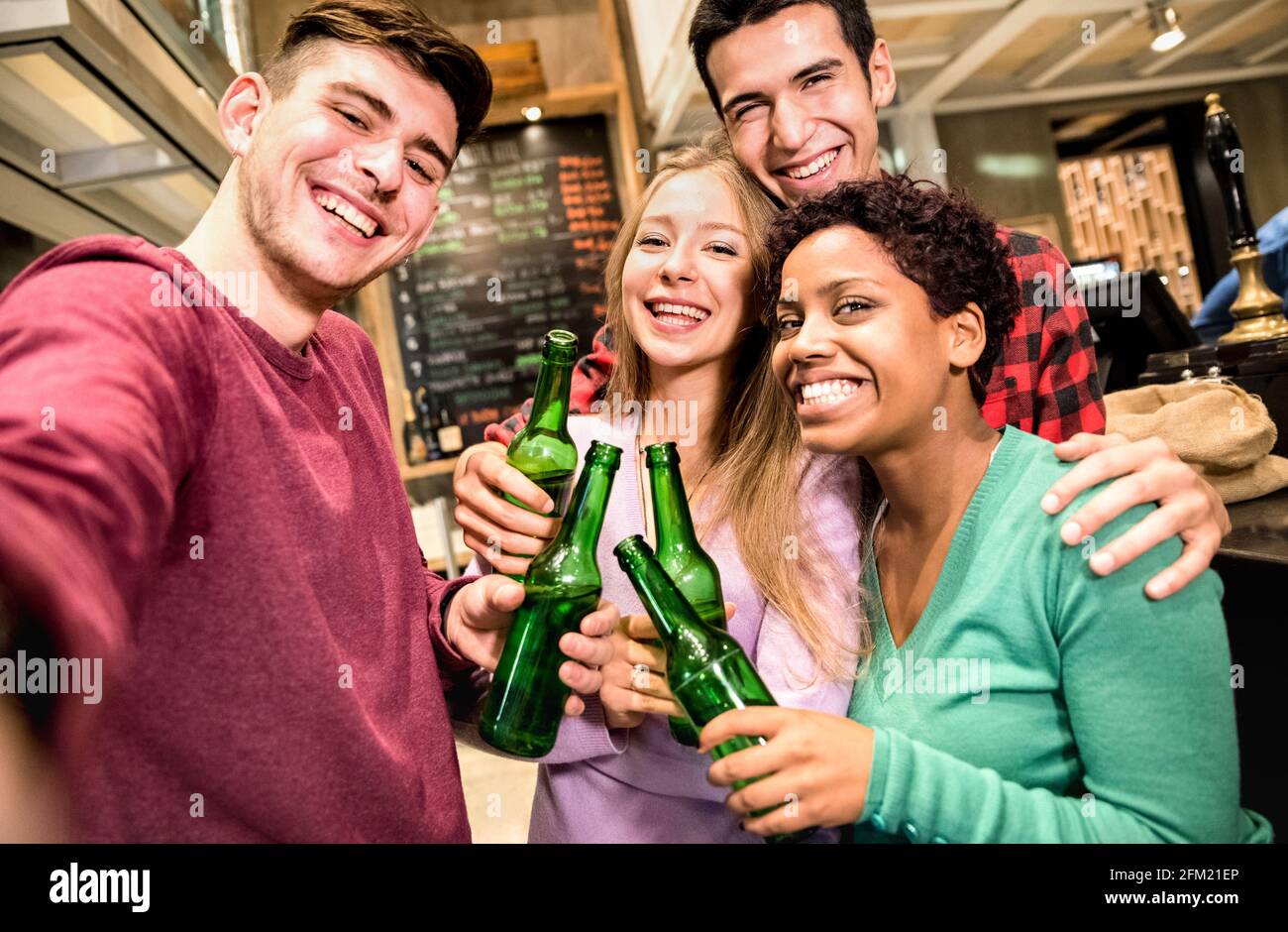 Multiracial friends taking selfie and drinking beer at fancy brewery restaurant - Friendship concept with young people enjoying time together Stock Photo