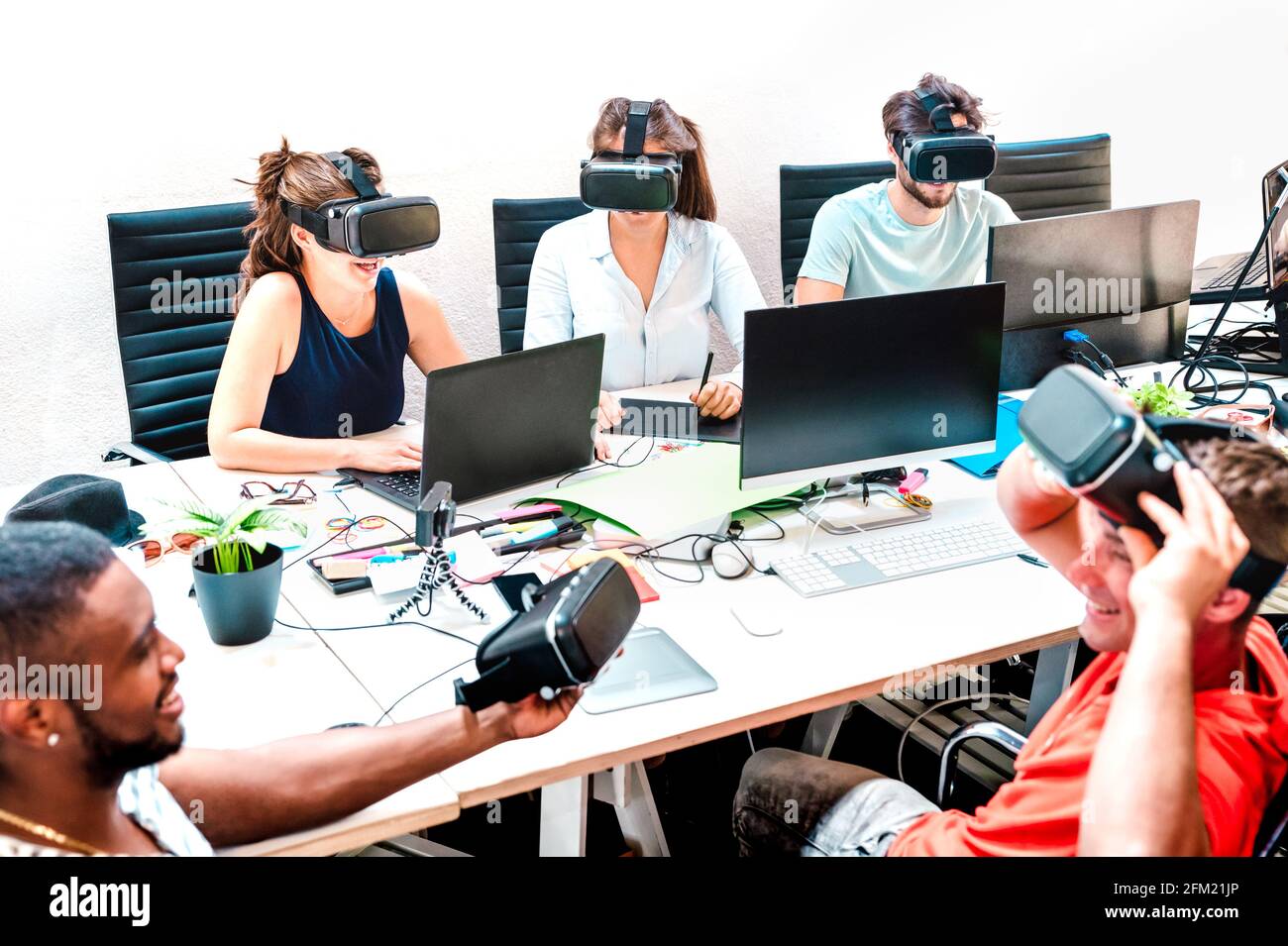 Young people employee workers having fun with vr virtual reality goggles in startup office - Human resource business concept at alternative studio Stock Photo