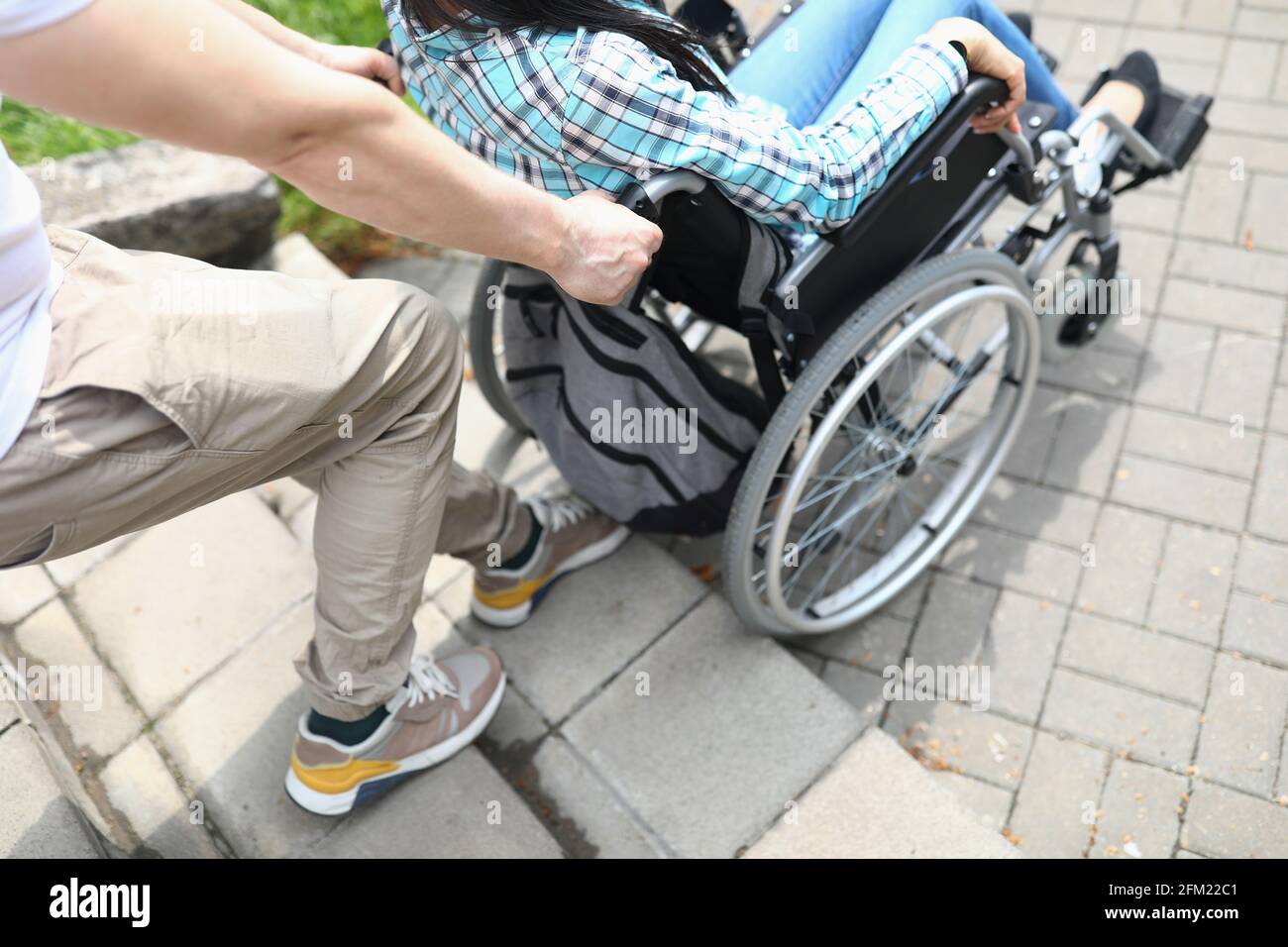 Man lifts a woman in wheelchair up stairs Stock Photo Alamy