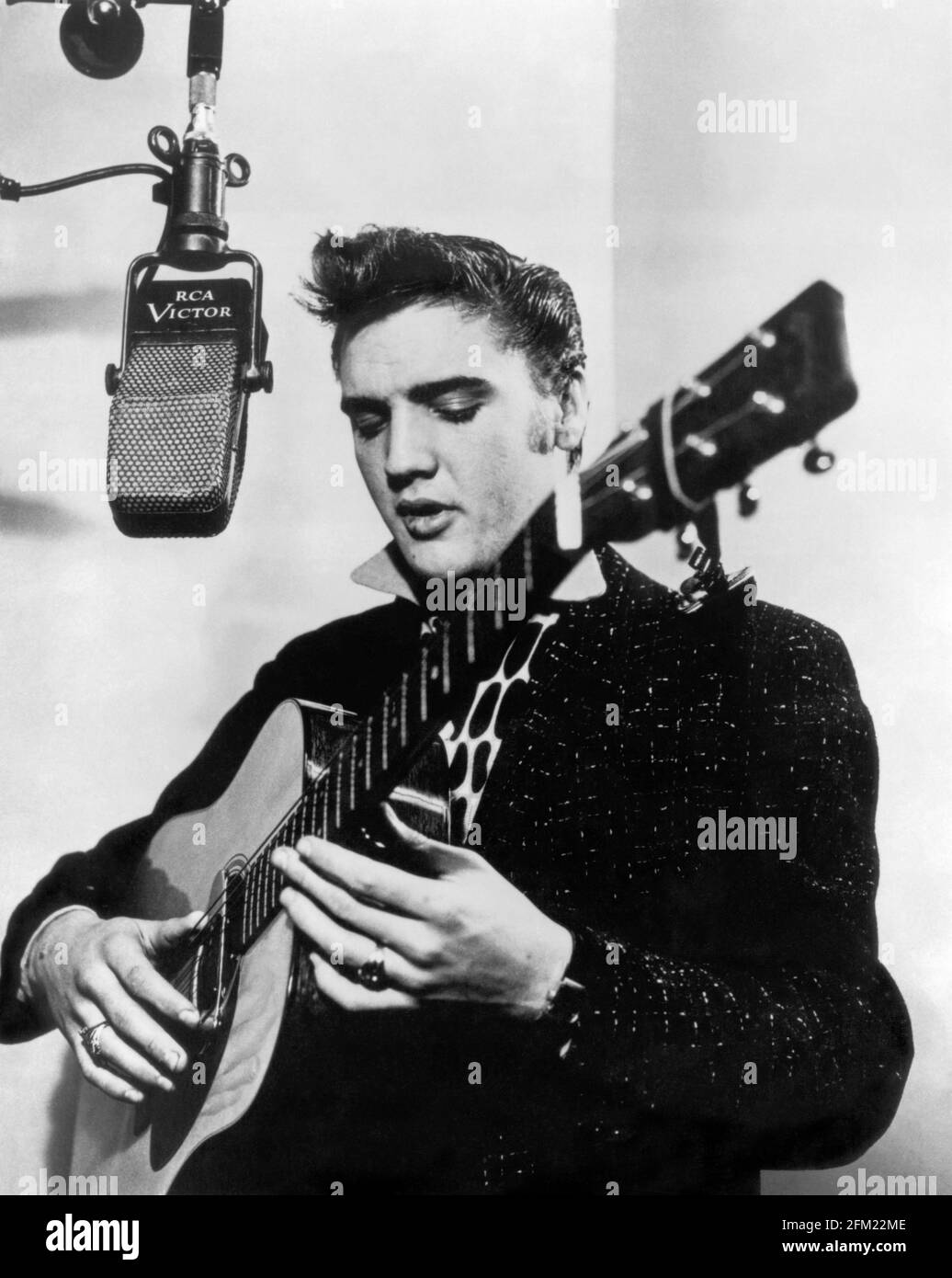Elvis Presley at RCA Victor Studio A (aka Studio 1) in New York City on December 1, 1955 with a borrowed guitar and a vintage RCA 44A microphone. (USA) Stock Photo