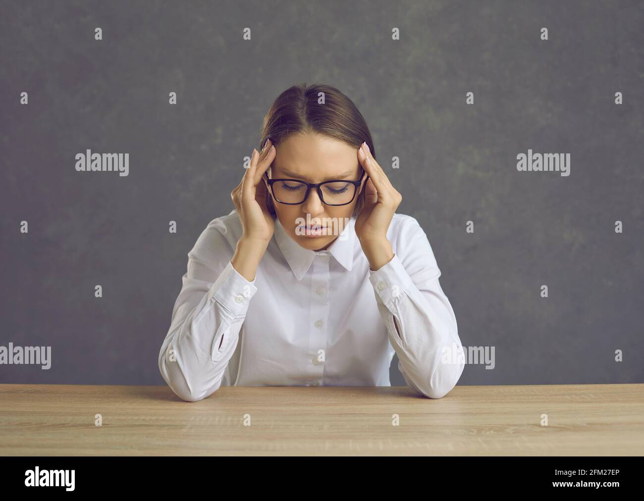 Tired woman office worker or teacher suffering from headache sitting at desk Stock Photo