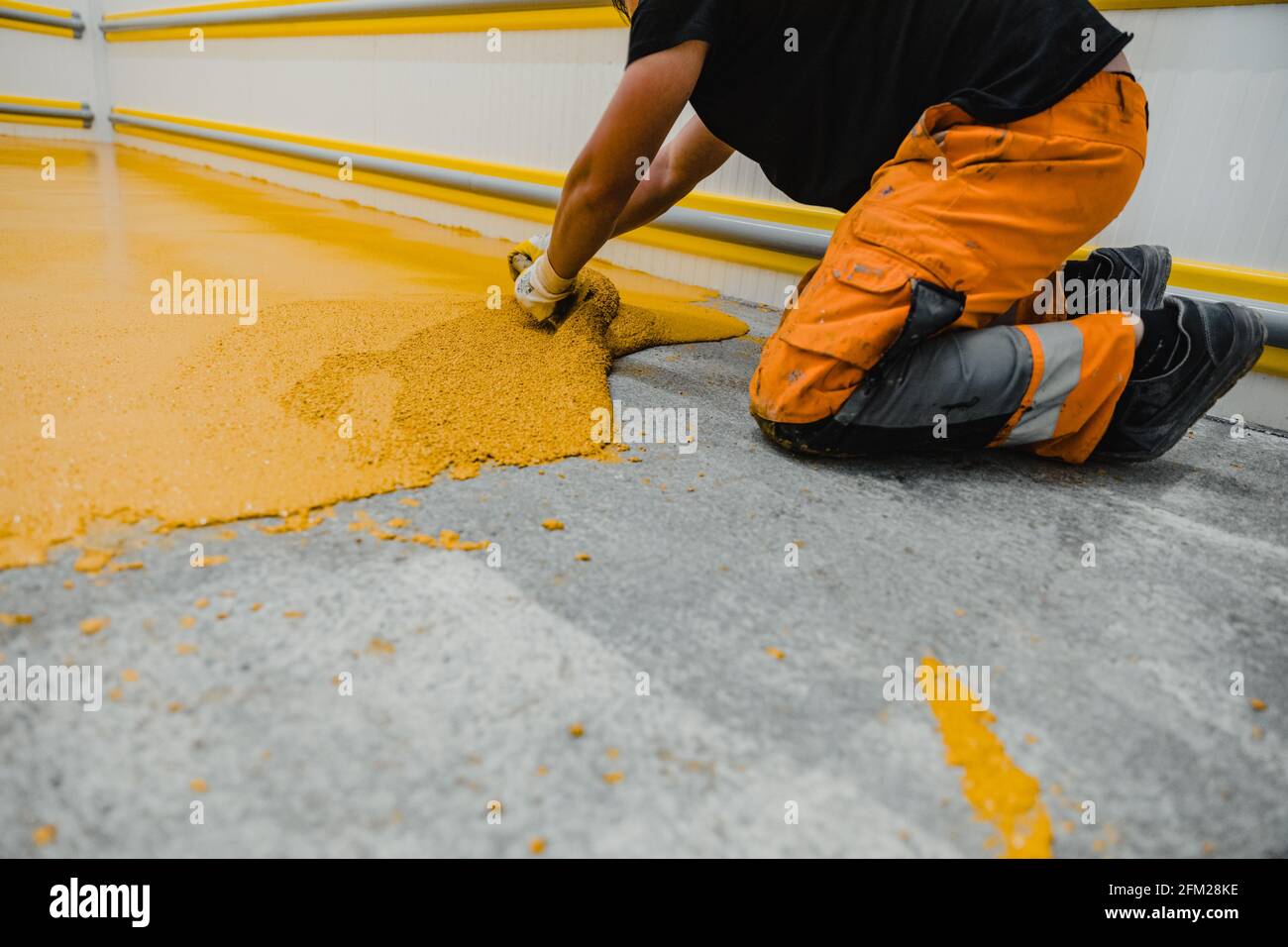 Worker applying epoxy and polyurethane flooring system.These easy-to-clean  products also have non-slip features Stock Photo - Alamy