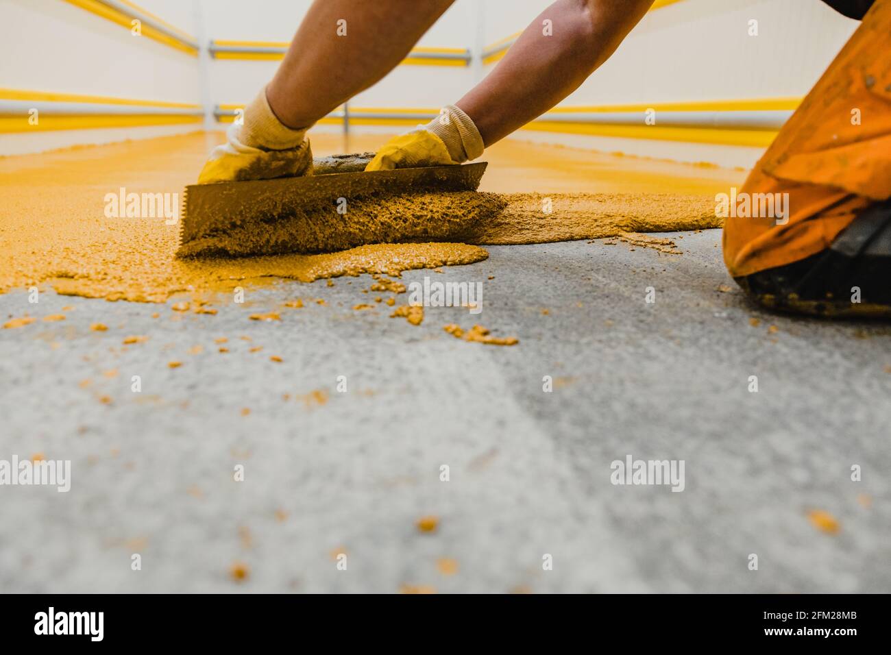 Worker applying epoxy and polyurethane flooring system.These easy-to-clean products also have non-slip features. Stock Photo