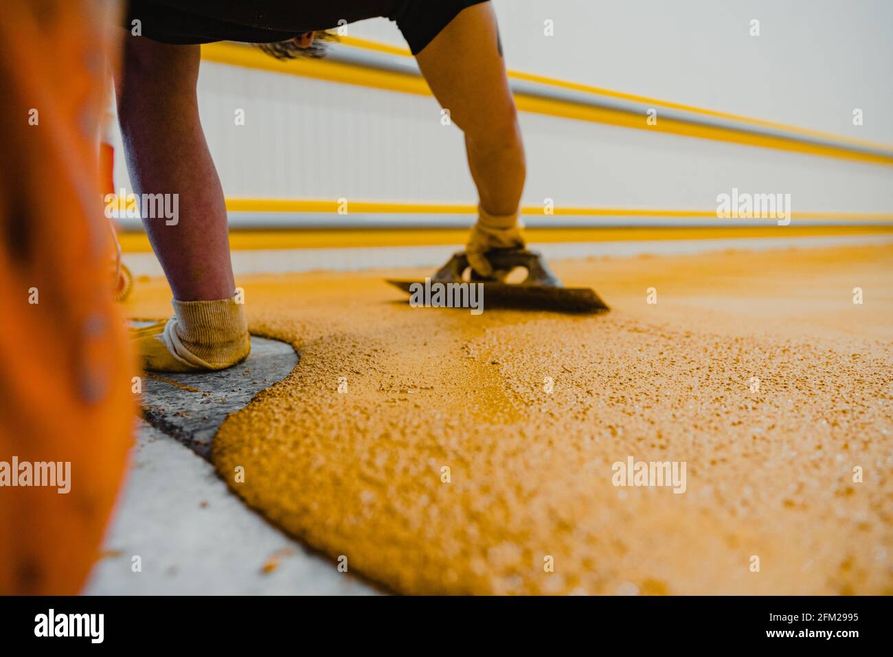 Worker applying epoxy and polyurethane flooring system.These easyto