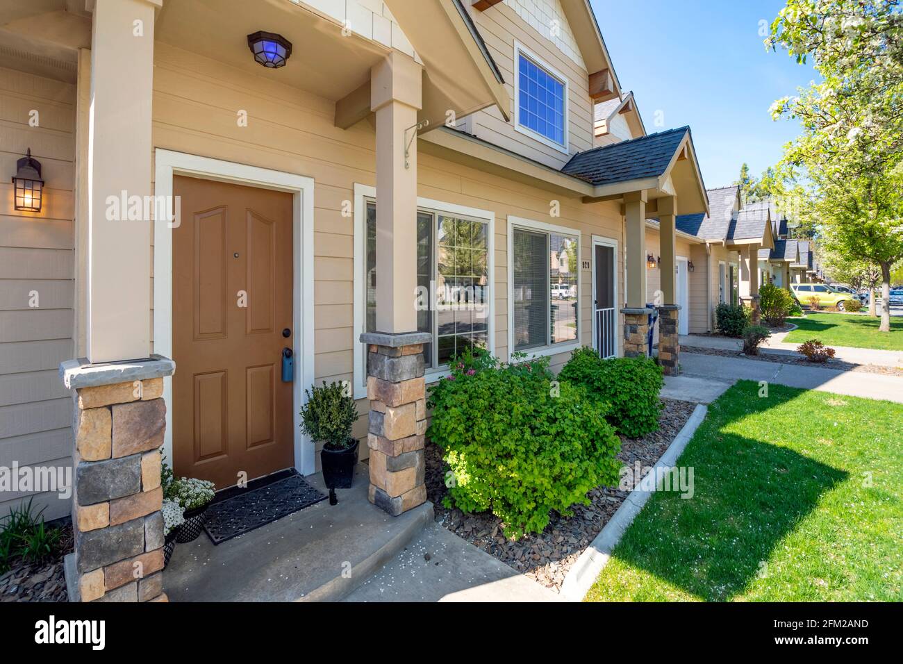 A home for sale with a lockbox on the doorknob within a row of suburban townhomes in the Inland Northwest. Stock Photo