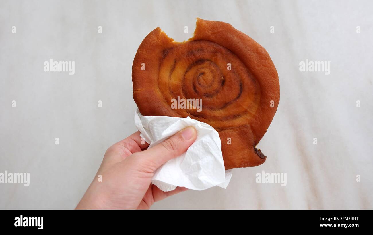 A hand holding a piece of Ham Chim Peng. Ham chim peng, meaning salty fried pancake, is a deep-fried hollow doughnut of Chinese origin. Stock Photo