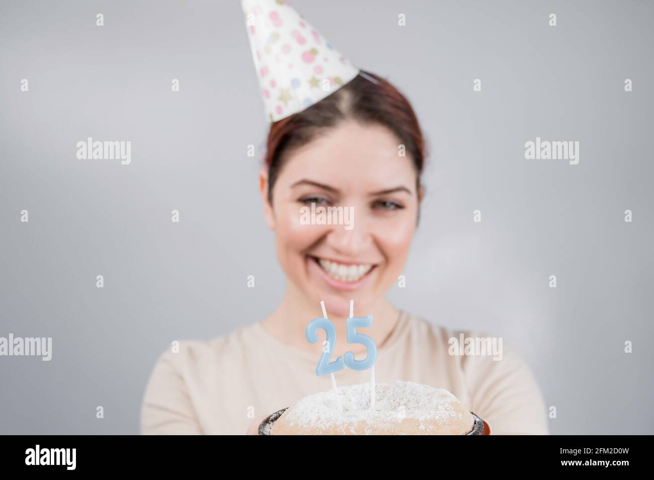 The happy woman makes a wish and blows out the candles on the 25th