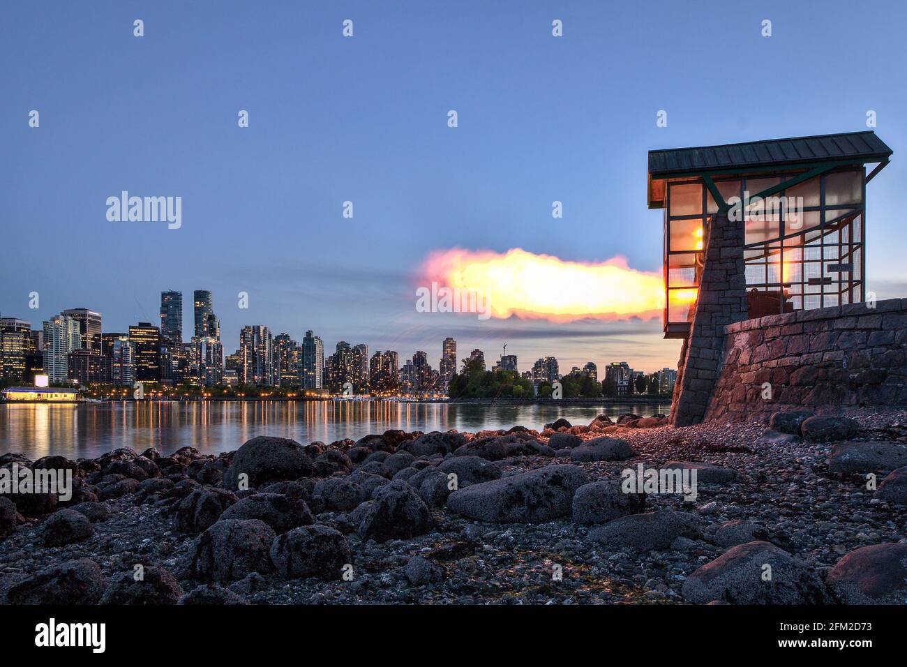 Vancouver Nine O'Clock Gun firing in dark during blue hour with cityscape in the background, Stanley Park, Vancouver, BC, Canada. Stock Photo