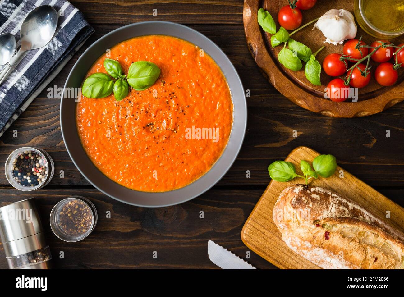 Creamy tomato soup with ripe tomatoes and fresh basil leaves besides a loaf of Ciabatta bread Stock Photo