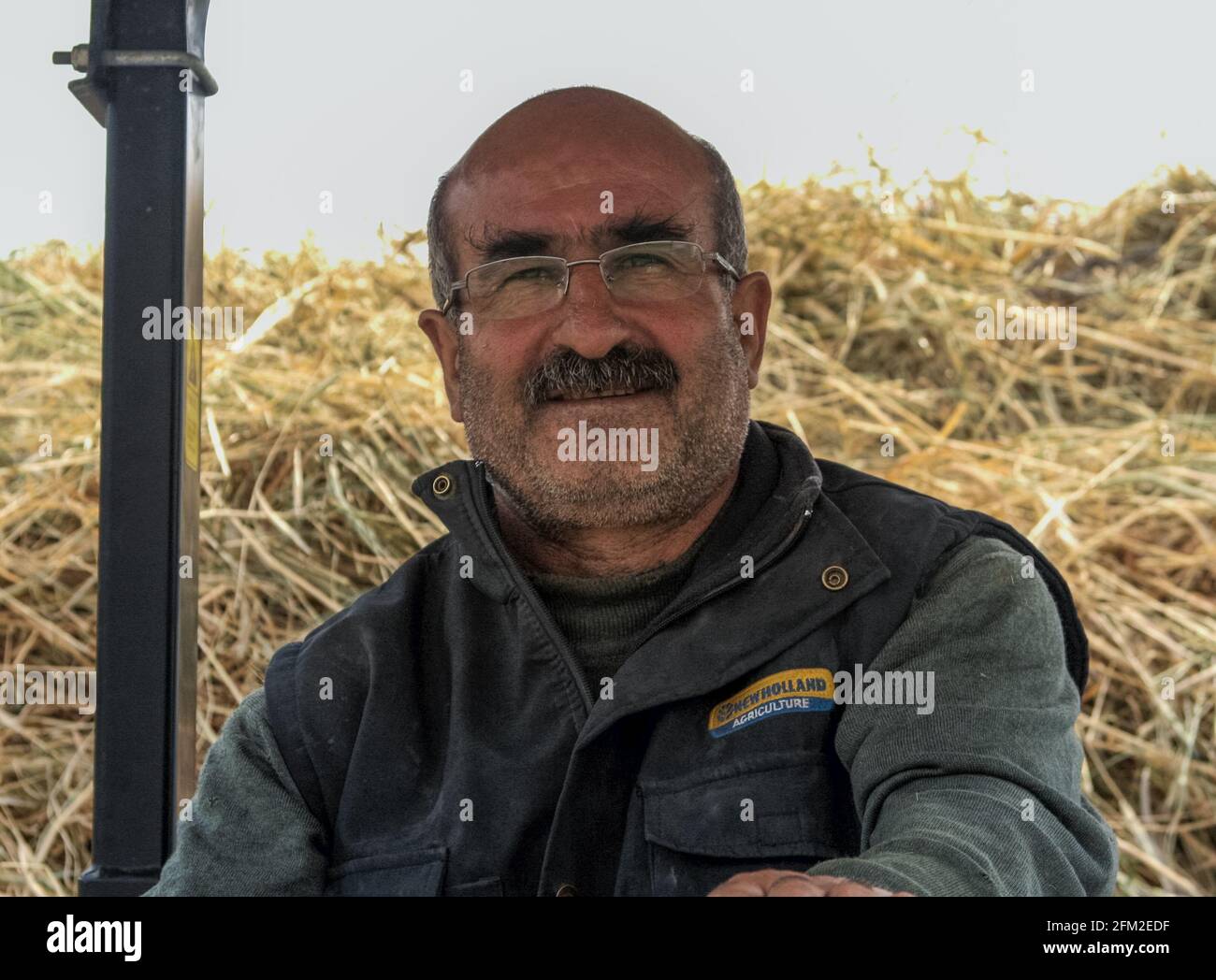 Gokceada, Canakkale - Turkey - May 07 2013: A male Turkish farmer driving a tractor carrying hay - Bademli koyu Stock Photo