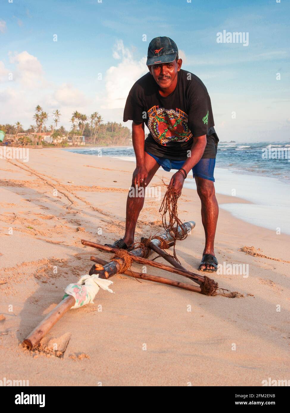 A local fisherman is busy adjusting the rope and wood on his stilt that will go into the water. Near Galle, Sri Lanka. Stock Photo