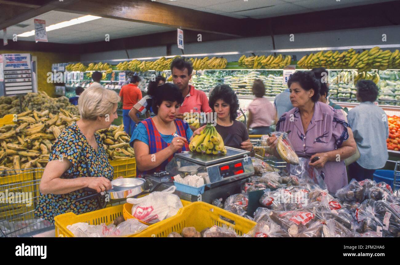 CARACAS, VENEZUELA, FEBRUARY 1988 - Women shopping in food store, clerk weighs bananas. Stock Photo