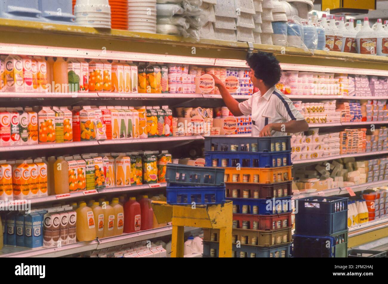 CARACAS, VENEZUELA, FEBRUARY 1988 - Man stocking shelves with yogurt in food supermarket. Stock Photo