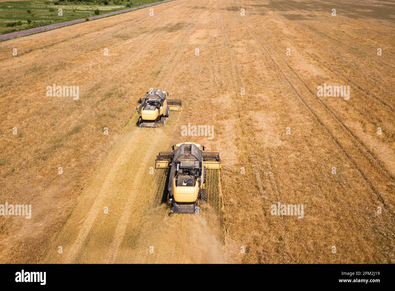 Aerial view of combine harvesters harvesting large yellow ripe wheat ...