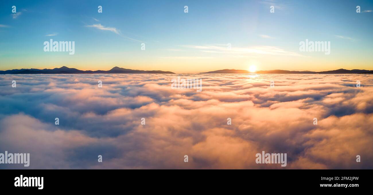 Aerial view of yellow sunset over white puffy clouds with distant ...