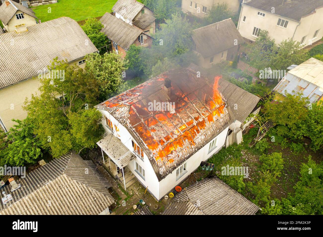 Aerial view of a house on fire with orange flames and white thick smoke ...