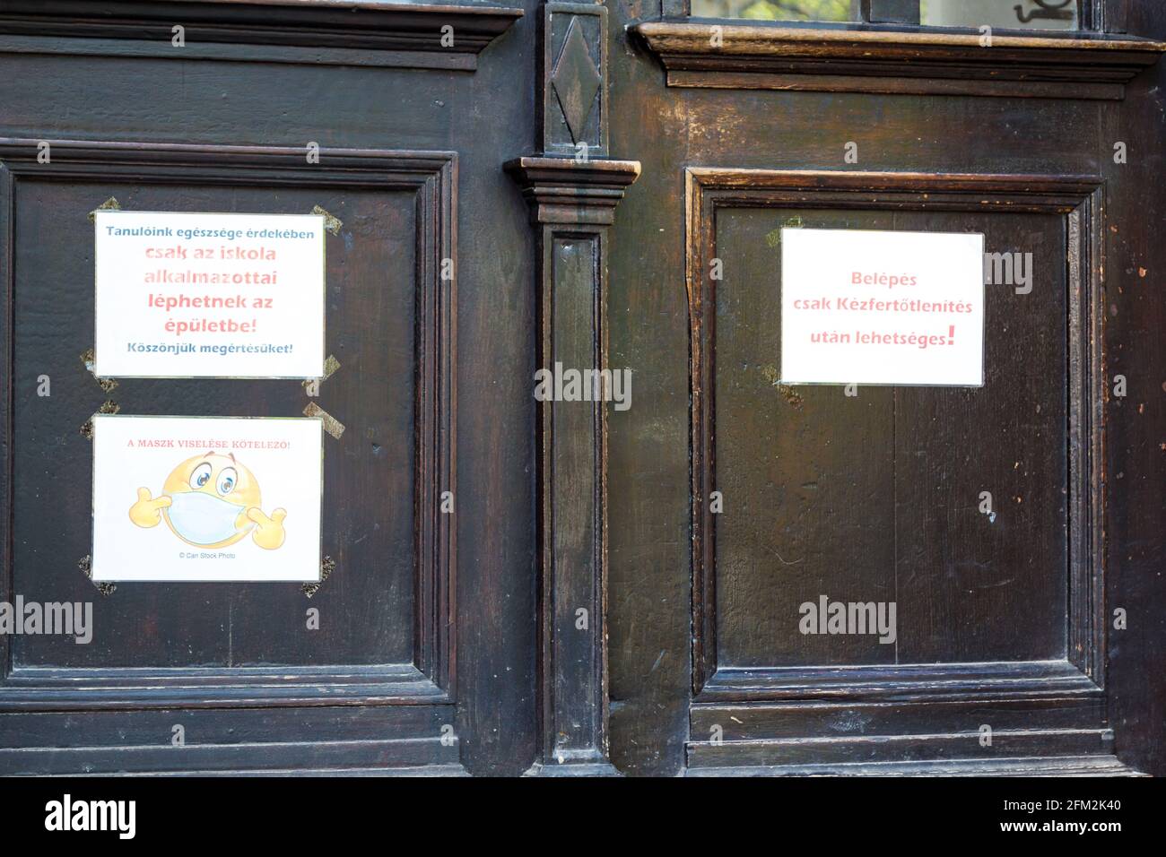 Warnings on school door: Wearing face mask is obligatory; Enter only after using hand sanitizer; Only school employees may enter; Sopron, Hungary Stock Photo