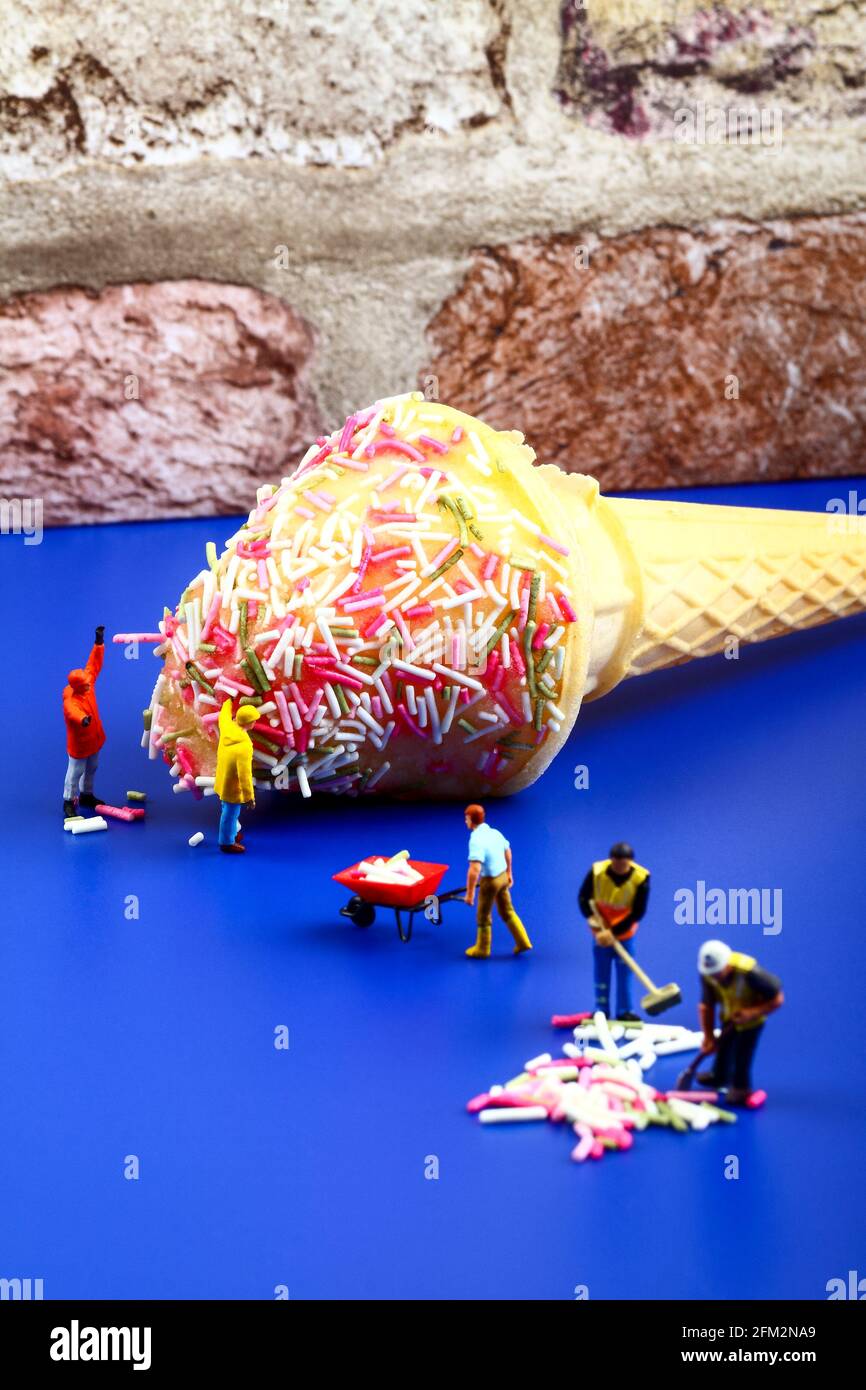 Miniature figure people topping an ice cream cone with hundreds and thousands Stock Photo